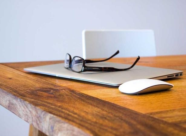 An image depicting a table with a laptop, mouse and pair of glasses ready to start online learning